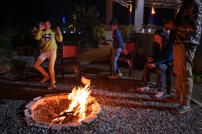 Two siblings dancing at the end of bonfire and enjoying thein childhood while their parents watch over them