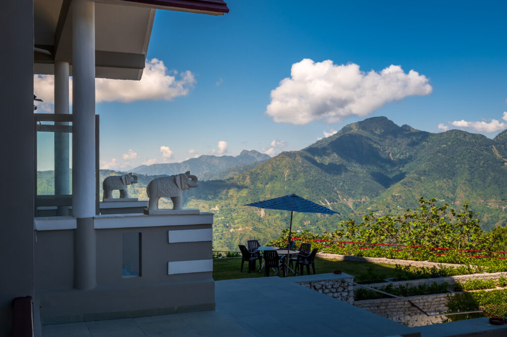 A statue of little white elephant in front of gigantic mountains